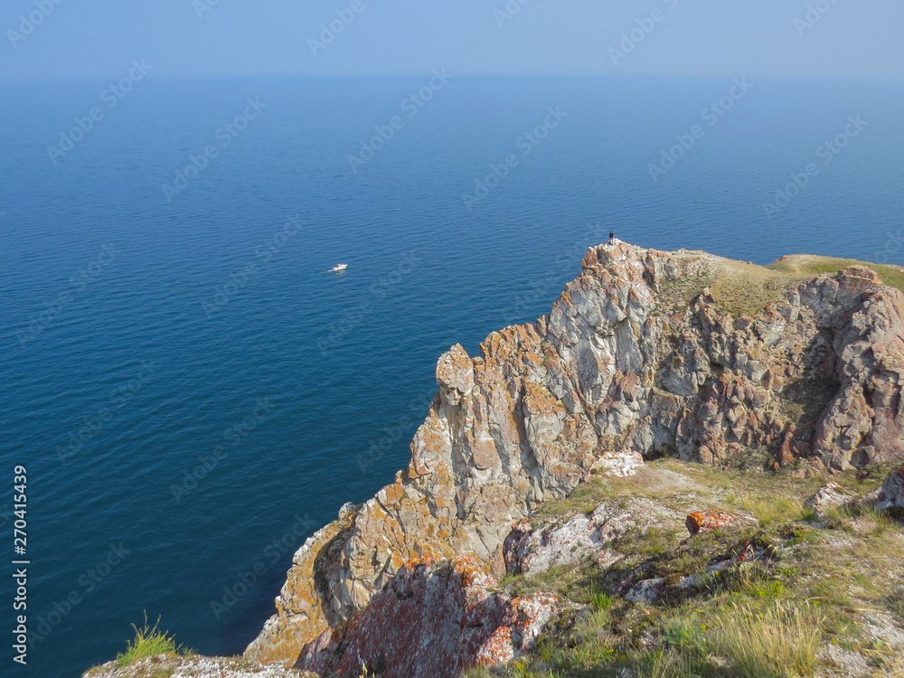 Tourist on the top of the cliff of Olkhon Island. View of Lake Baikal .