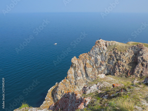 Tourist on the top of the cliff of Olkhon Island. View of Lake Baikal .