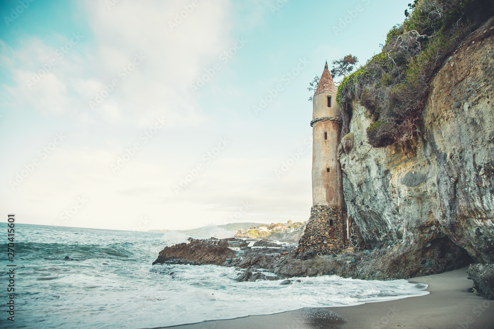 A rustic seashore scene featuring an old castle tower and cliffside
