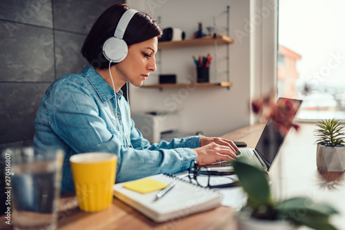 Woman using laptop and listening music on a headphones photo