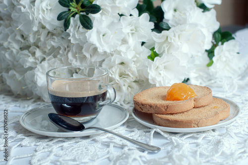 Apparecchiatura romantica del tavolo della colazione, con fiori di azalea bianca, tazza di caffè e biscotti con marmellata