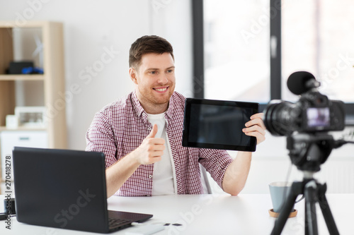 blogging, videoblog and people concept - male blogger with camera recording video review of tablet pc computer and showing thumbs up at home office