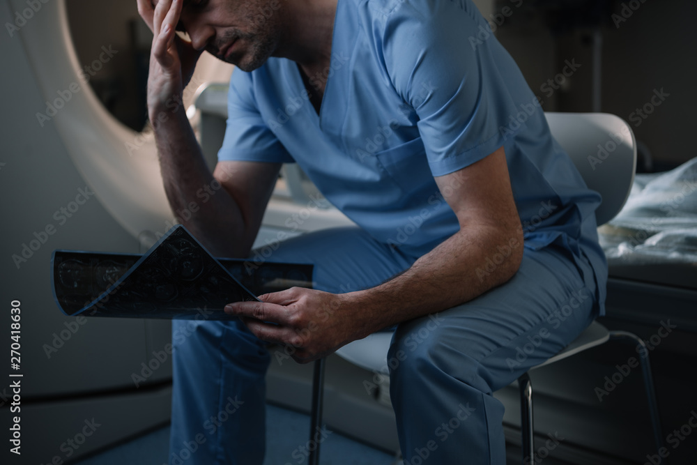 tired radiologist holding x-ray diagnosis while sitting near computed ...
