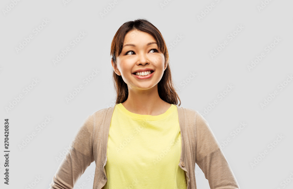 people, ethnicity and portrait concept - happy asian young woman looking up over grey background people, ethnicity and portrait concept - happy asian young woman looking up over grey background
