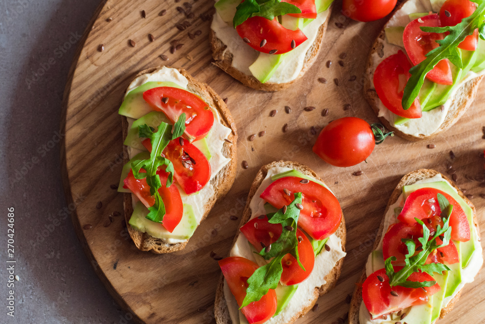 Fresh  toasts with avocado and tomatoes on wooden table 