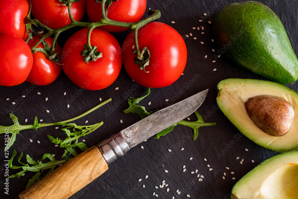 Tomatos and avocado on black table close up, colorful healthy food Tomatos and avocado on black table close up, colorful healthy food