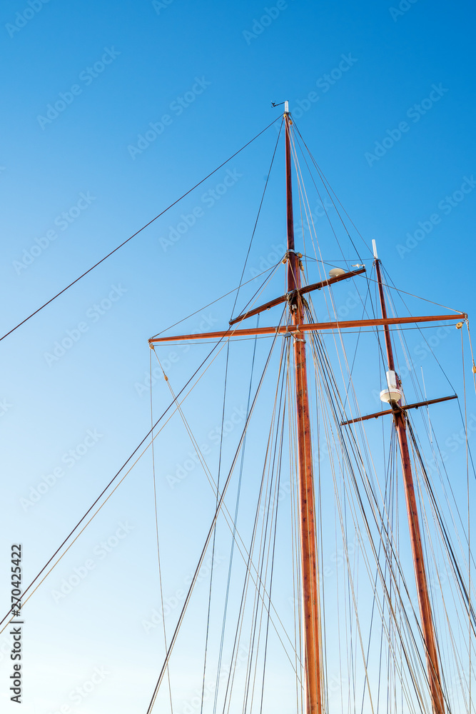 Mast on a yacht with a lot of ropes against a sunny blue sky on a summer day. Bottom view Mast on a yacht with a lot of ropes against a sunny blue sky on a summer day. Bottom view