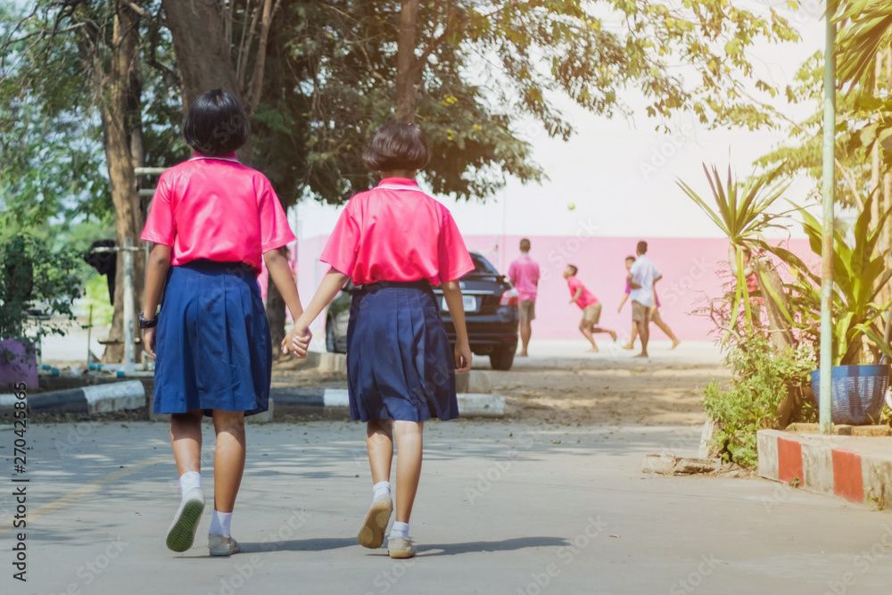 Back view of happiness primary girl students in pink shirt and blue skirt walk to classrooms with their friends. Back view of happiness primary girl students in pink shirt and blue skirt walk to classrooms with their friends.