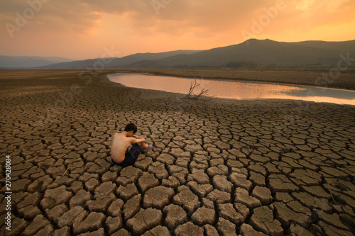 Water crisis, Sad Children sitting on cracked earth near drying water at the river metaphor climate change, Global warming, Environment pollution.