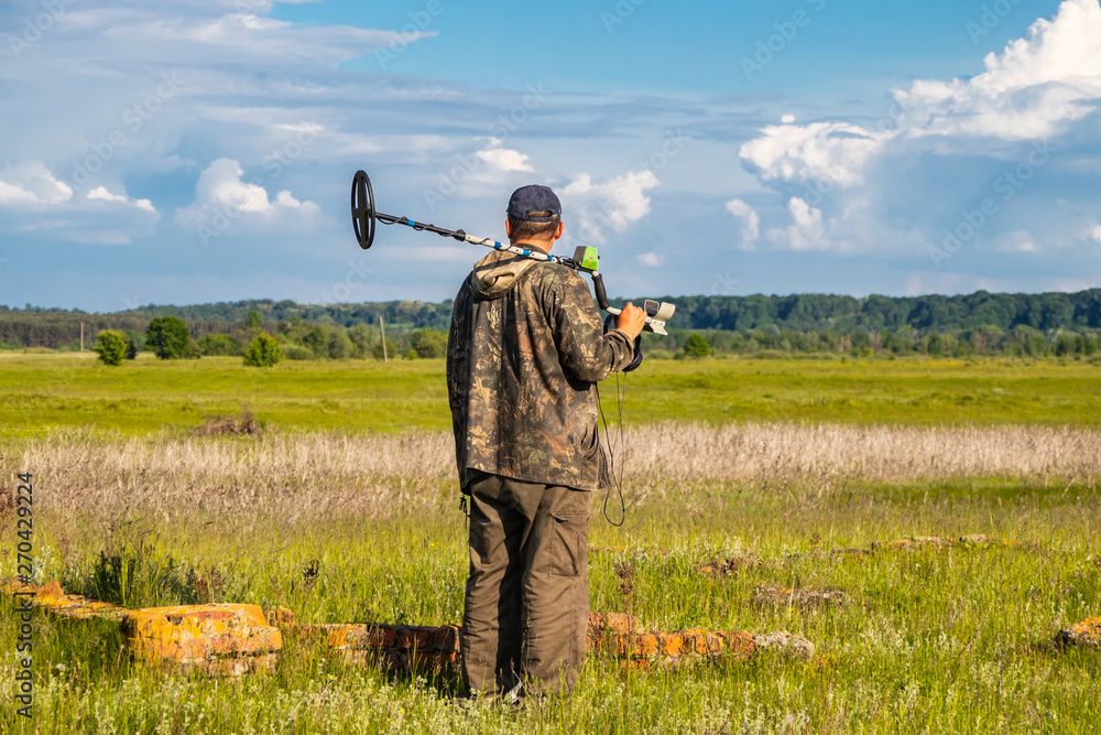 Treasure hunter in the field with a metal detector Treasure hunter in the field with a metal detector