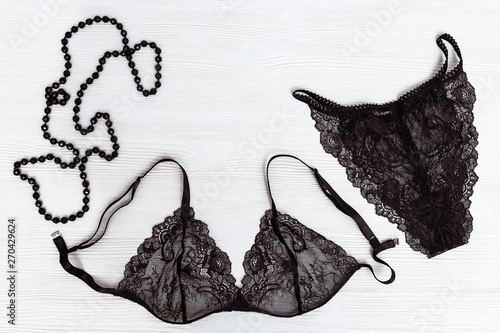 Black Lace bra and panty, female adornment Black beads on white wooden background. Womans lingerie. Beauty, fashion, blogger concept. Top view.
