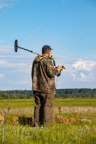 Treasure hunter in the field with a metal detector © Taras