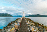 Biała latarnia morska na kamienistej skalnej wyspie o zachodzie słońca. Godoya Norwegia