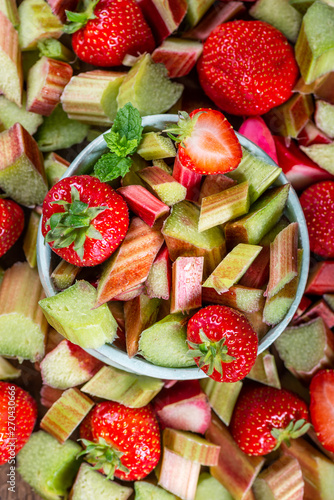 Close up of Pieces of Raw and Freshly Cut Rhubarb and Strawberries on Dark Rustic Background