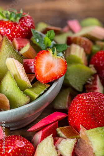 Close up of Pieces of Raw and Freshly Cut Rhubarb and Strawberries on Dark Rustic Background