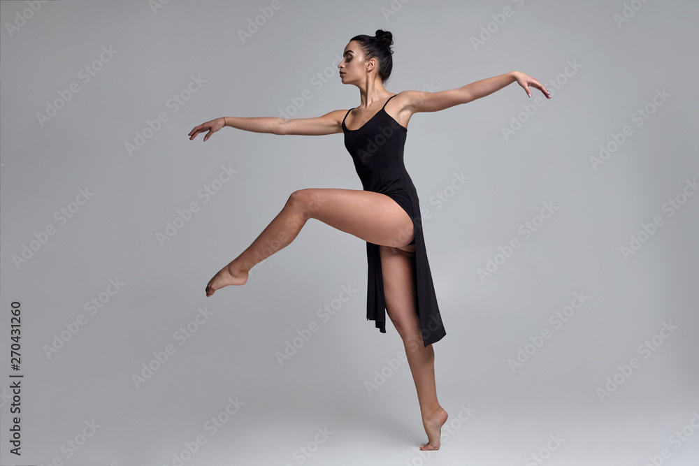 Dancing ballerina in a black dress. Contemporary graceful performance on a gray background. Dancing ballerina in a black dress. Contemporary graceful performance on a gray background.