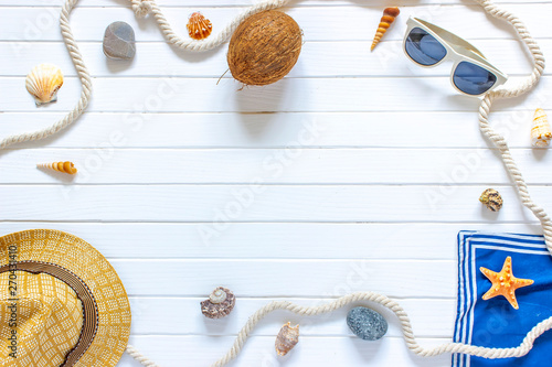 Beautiful summer vacation, beach accessories, sunglasses, hat, rope, and shells on white wooden background.