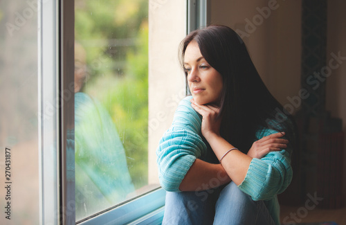 Fototapet woman sitting on the window sill