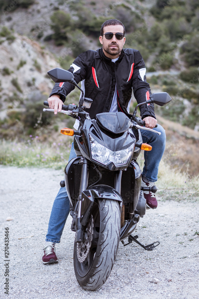 Young man biker with his black motorbike ready to drive Young man biker with his black motorbike ready to drive