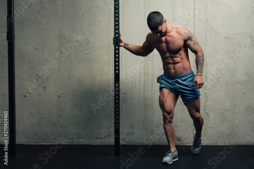 Young strong man posing and flexing his quadriceps legs muscles