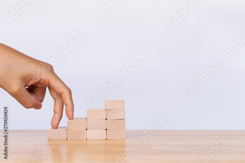 Walking his fingers up wooden cube stack a staircase on white background. Concept of success, winner, victory or top ranking