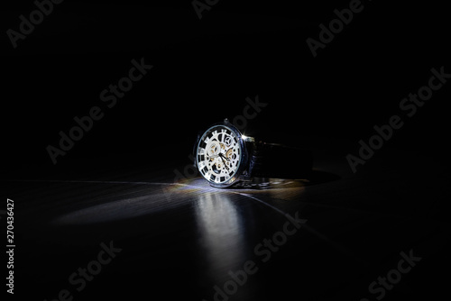 Wrist watch in the dark under light.
