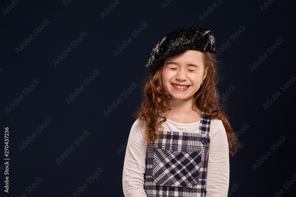 Stylish brunette kid is posing in studio on a black background. Children's fashion. Stylish brunette kid is posing in studio on a black background. Children's fashion.