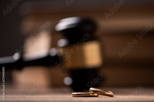 Judge gavel with wedding rings on wooden table
