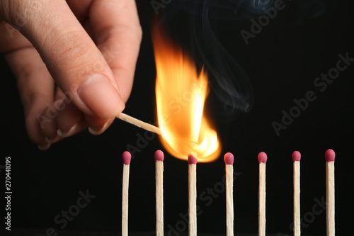Woman igniting line of matches on black background, closeup. Space for text