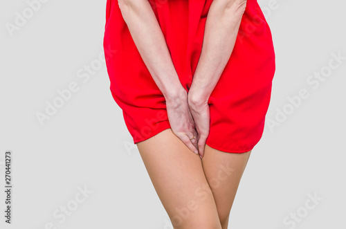 Woman in a red dress holding hands between legs. Experiencing pain, discomfort. Women's health, gynecology photo