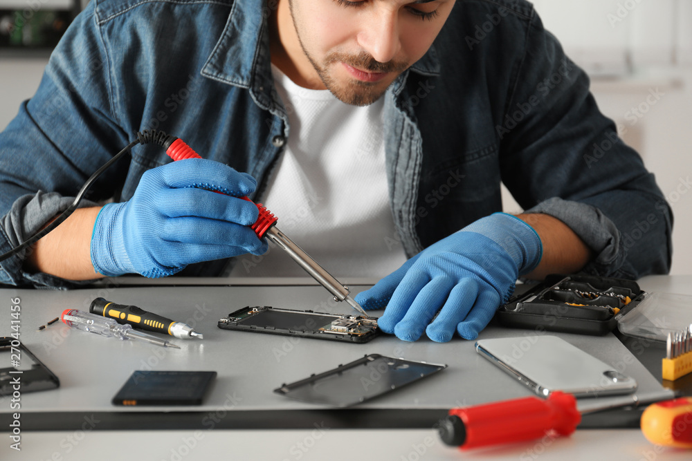 Technician repairing broken smartphone at table, closeup Technician repairing broken smartphone at table, closeup