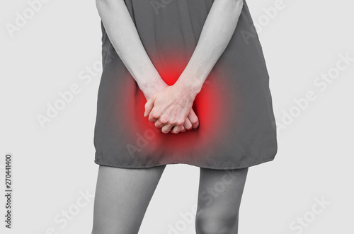Woman in a red dress holding hands between legs. Experiencing pain, discomfort. Women's health, gynecology