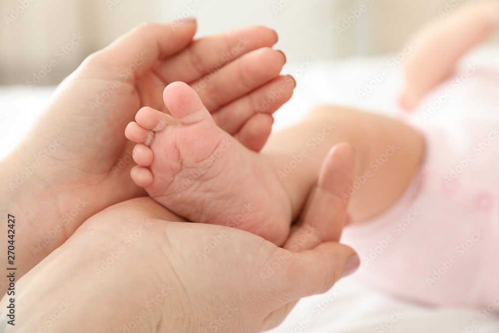 Mother holding baby's foot on bed, closeup Mother holding baby's foot on bed, closeup