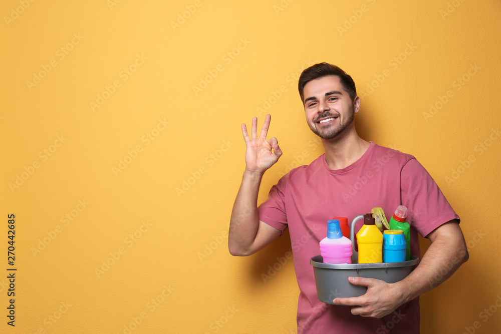 Man with basin of detergents on color background. Space for text Man with basin of detergents on color background. Space for text