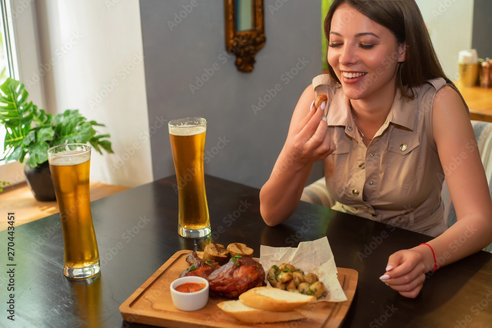 Beautiful girl enjoys chicken meal with beer in restaurant Beautiful girl enjoys chicken meal with beer in restaurant