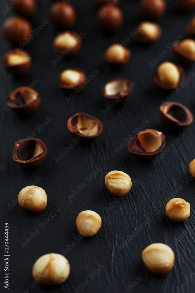 Purified and shell repeats macadamia nuts on black textural stone background. Healthy eating concept Purified and shell repeats macadamia nuts on black textural stone background. Healthy eating concept