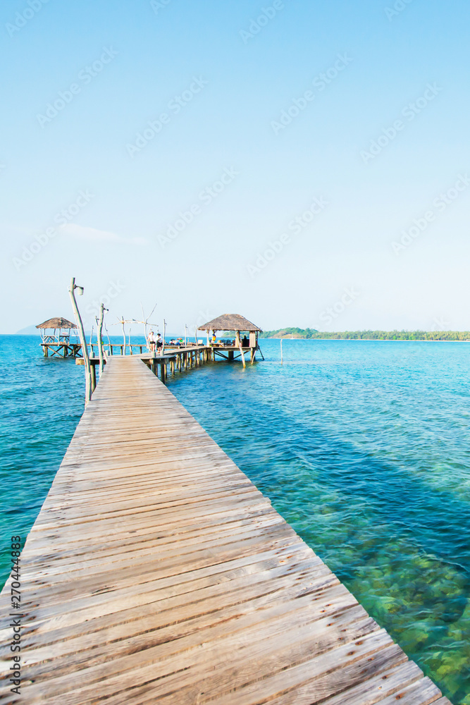 Empty wooden bridge extending into the blue sea.