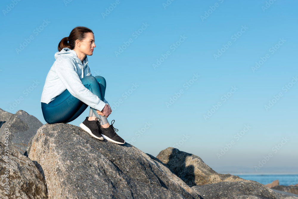 Woman sitting on rocks thinking