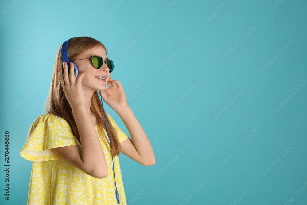 Teenage girl enjoying music in headphones on color background. Space for text Teenage girl enjoying music in headphones on color background. Space for text