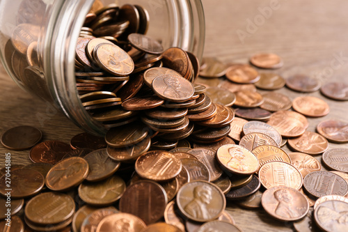 Glass jar with coins on table, closeup. Money saving concept photo