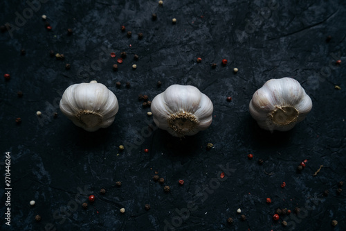 Three whole garlic bulbs isolated on black stone table background. Flat lay. Top view