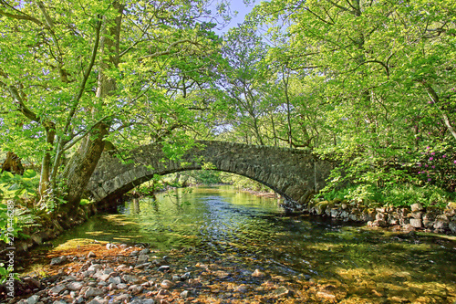 An ancient stone pack horse bridge over a river in the English Lake District