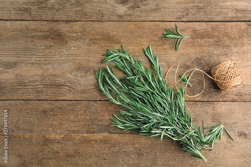 Fresh rosemary branches and twine on wooden table, flat lay. Space for text