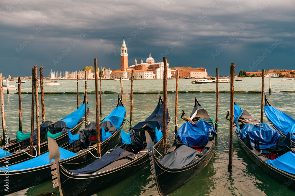 Gondolas parked beside  Riva degli Schiavoni in Venice, Italy. View of  Venetian Lagoon. San Giorgio Maggiore church on background.