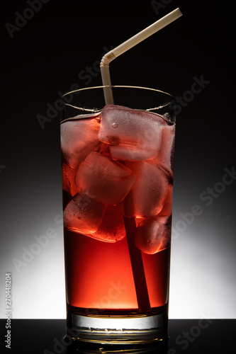 Isolated glass with a red cocktail and ice-cubes