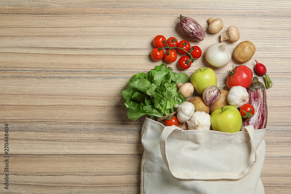 Overturned cloth bag with vegetables and apples on wooden background, flat lay. Space for text Overturned cloth bag with vegetables and apples on wooden background, flat lay. Space for text