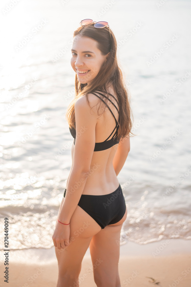 Beautiful woman in black bikini is relaxing on the beach, summer concept Beautiful woman in black bikini is relaxing on the beach, summer concept