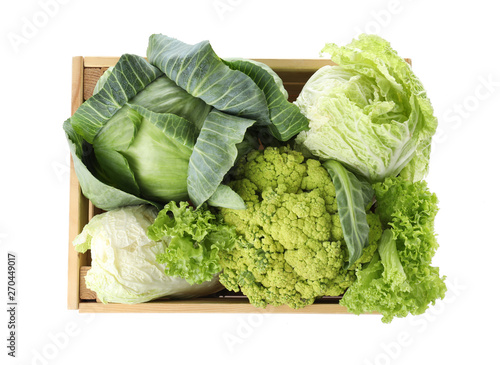 Wooden crate full of fresh green vegetables on white background, top view photo