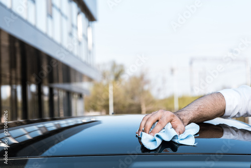 cropped view of man cleaning black car with white cloth near building © LIGHTFIELD STUDIOS