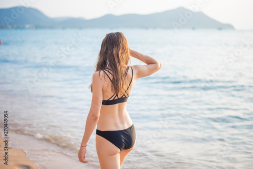 Beautiful woman in black bikini is relaxing on the beach, summer concept